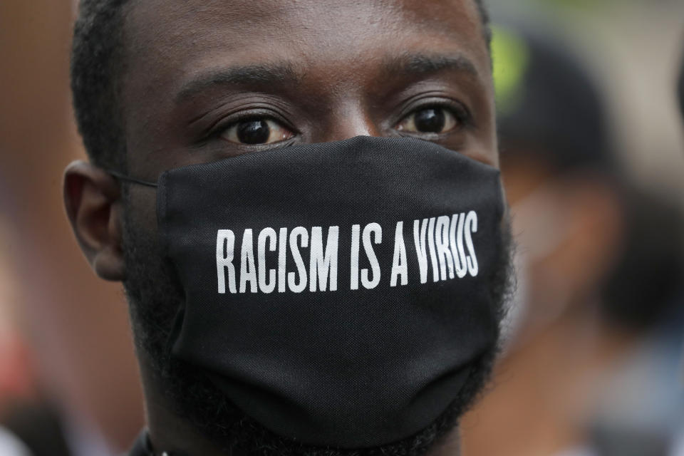 A protester wears a face mask in front of the US embassy, during the Black Lives Matter protest rally in London, Sunday, June 7, 2020, in response to the recent killing of George Floyd by police officers in Minneapolis, USA, that has led to protests in many countries and across the US. (AP Photo/Frank Augstein)