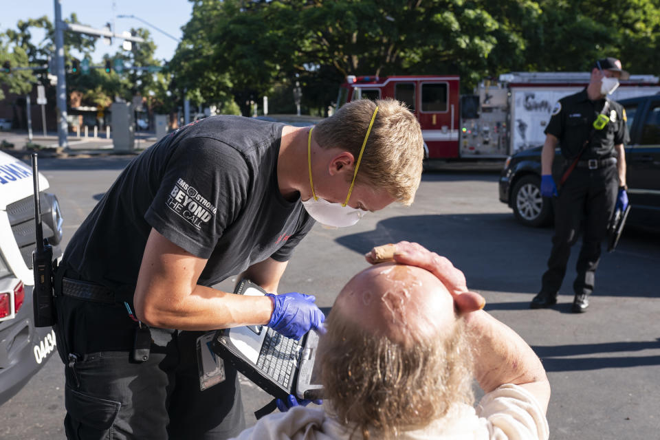 A paramedic with Falck Northwest ambulances treats a man experiencing heat exposure during a heat wave, Saturday, June 26, 2021, in Salem, Ore. (AP Photo/Nathan Howard)