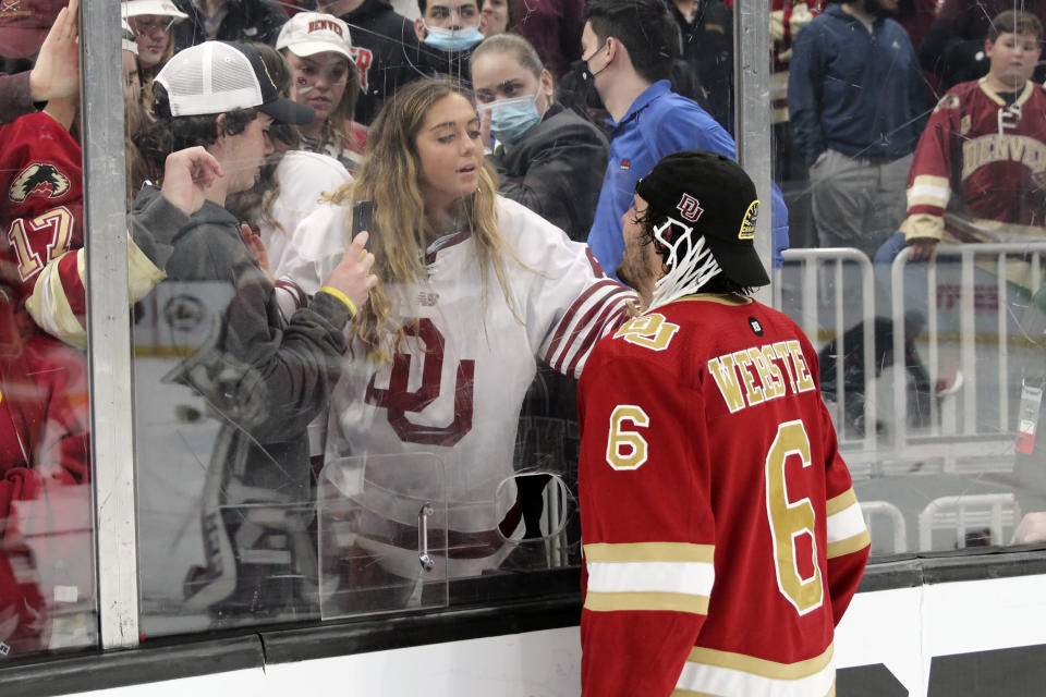 This photo provided by Sunny Hilliard shows Denver Pioneers NCAA college hockey player McKade Webster (6) looking through the glass towards his sister, MaKenna, after Denver beat Minnesota State to win their ninth NCAA national hockey title, in Boston, April 9, 2022. McKade Webster and the Pioneers face Boston University in a 2024 Frozen Four semifinal game, with the winner advancing to the title game. In the Webster family, hockey runs deep. So does winning on the ice. Makenna has now won two NCAA national titles and McKade has one courtesy of the Pioneers' win in 2022. (Sunny Hilliard via AP)