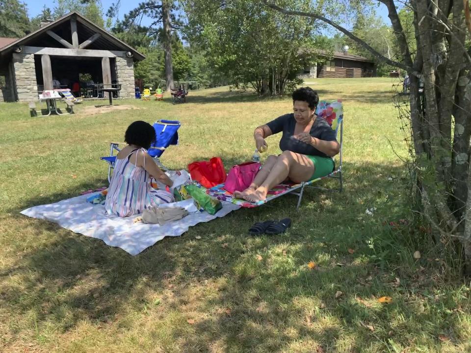 Rosa Chavez, of New York City, applies sunscreen as she and friend Arlene Rodriguez visit Promised Land State Park, Sunday, July 24, 2022 in Pennsylvania's Pocono Mountains in Greentown, Pa. Residents around the Northeast braced for potentially record-breaking temperatures Sunday as a nearly weeklong hot spell continued. (AP Photo/Jeff McMillan)