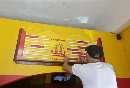 A worker adjusts a menu at the private cafeteria Mcdunald in Villa Clara province, Cuba, November 14, 2015. REUTERS/Enrique de la Osa