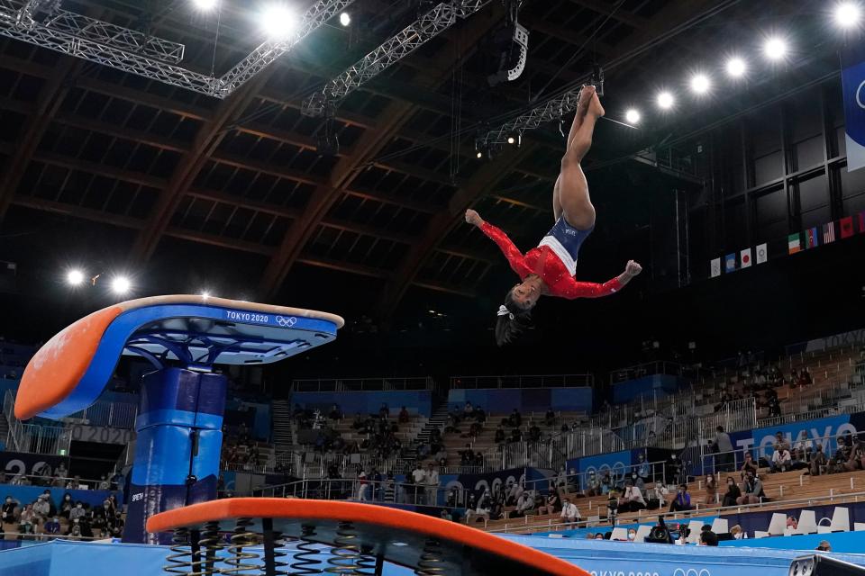 Biles, seen in the air, appears to be contorting her face away from her body