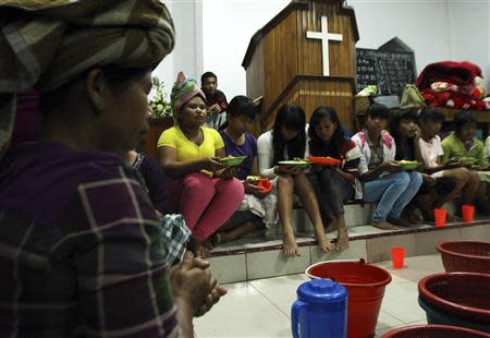 Villagers pray before taking their dinner inside a church used as temporary shelter as a safety precaution after Sinabung volcano erupted at Payung village in Karo district, Indonesia's north Sumatra province, November 3, 2013. REUTERS/Roni Bintang