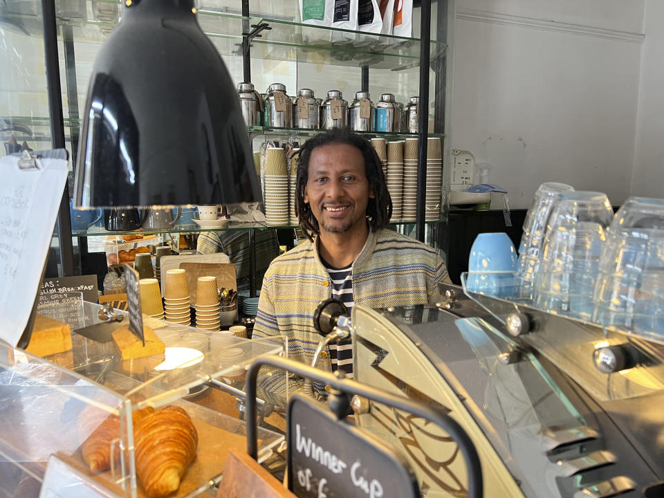 Anteneh Mulu, 46, poses behind the counter after serving a customer at his coffee shop, The Ethiopian Coffee Company, in central London on Thursday, Aug. 31, 2023. Mulu and his business partner Polly Hamilton, 79, opened their shop in 2013. The London-based International Coffee Organization has declared this Sunday, Oct. 1, as International Coffee Day. (AP Photo/Almaz Abedje)