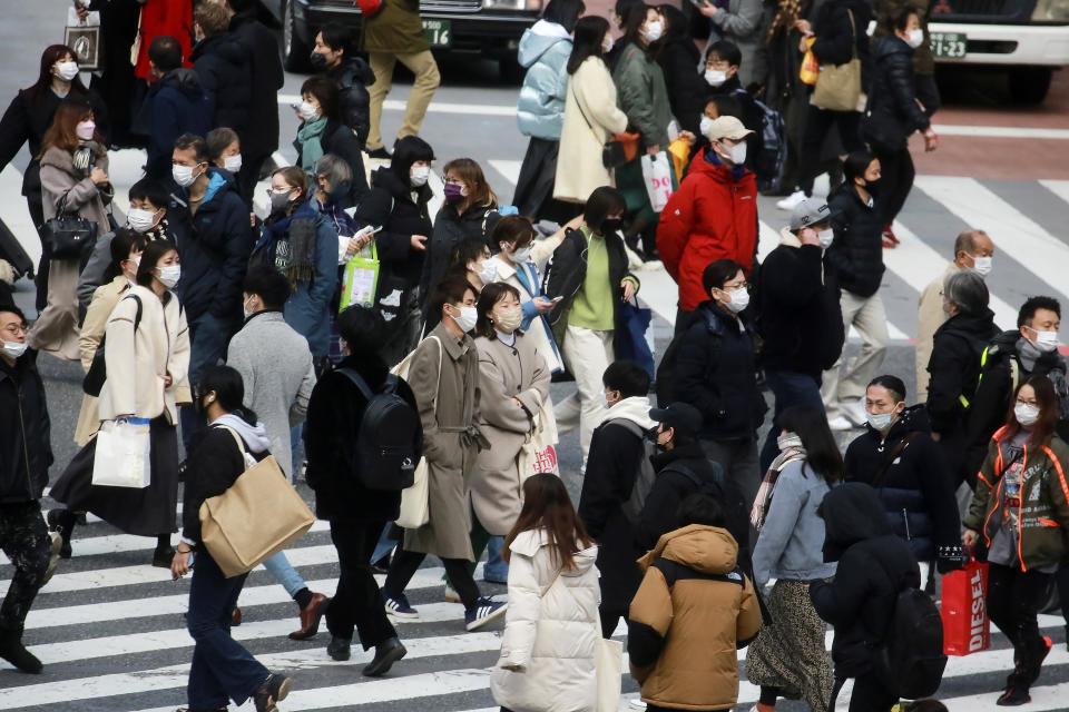 People wearing face masks to help protect against the spread of the coronavirus walk along the street in Tokyo, Wednesday, Jan. 19, 2022. The Japanese government announced Wednesday, Jan. 19, 2022, it will place Tokyo and a dozen other areas under a near-emergency status for COVID-19 effective Friday, allowing local leaders to shorten hours for eateries, as a surge in omicron cases threatens to paralyze society. (AP Photo/Koji Sasahara)