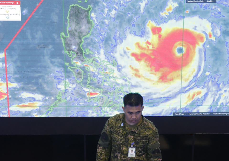 A member of the Philippine Air Force stands in front of a satellite image of Typhoon Mangkhut, locally named Typhoon Ompong, at the National Disaster Risk Reduction and Management Council operations center in metropolitan Manila, Philippines on Thursday, Sept. 13, 2018. Philippine officials have begun evacuating thousands of people in the path of the most powerful typhoon this year, closing schools and readying bulldozers for landslides. (AP Photo/Aaron Favila)