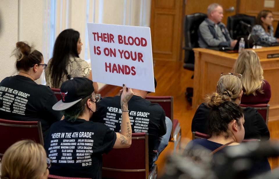 A woman holds a sign reading “Their blood is on your hands” during a Uvalde school board meeting on Oct. 10.