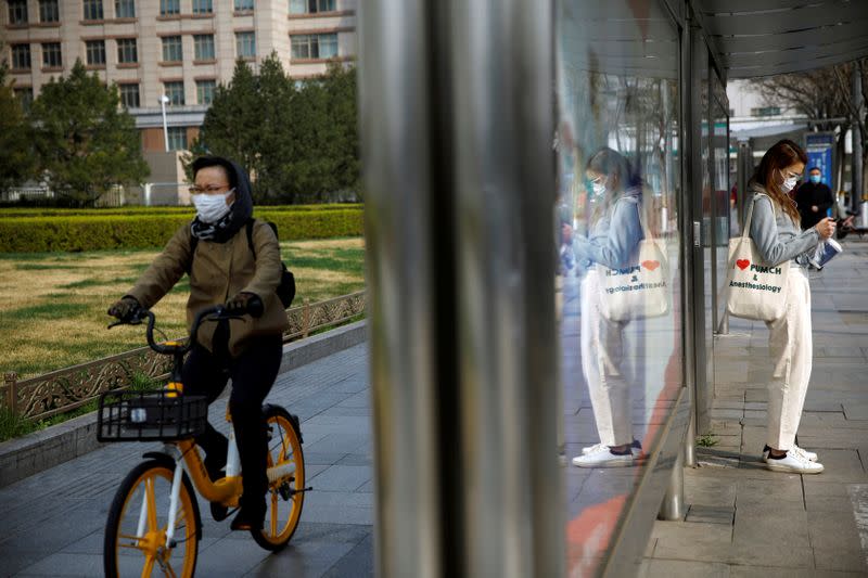 People wear face masks near a bus stop on a street following an outbreak of the coronavirus disease (COVID-19), in Beijing, China