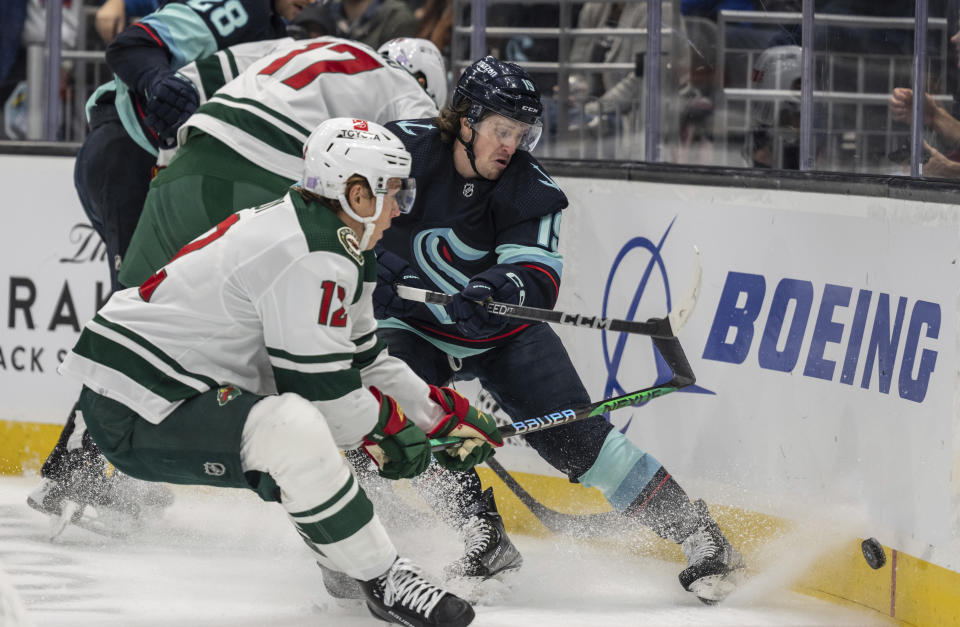 Seattle Kraken forward Jared McCann, right, and Minnesota Wild forward Matt Boldy compete for the puck along the boards during the first period of an NHL hockey game Friday, Nov. 11, 2022, in Seattle. (AP Photo/Stephen Brashear)
