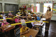 A teacher and students wearing hats designed for space keeper, practice social distancing to help curb the spread of the coronavirus at Ban Pa Muad School in Chiang Mai, north of Thailand, Friday, July 3, 2020. (AP Photo/ Wichai Taprieu)