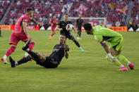 Houston Dynamo's Daniel Steres, left, falls as St. Louis City goalkeeper Roman Burki, right, reaches for the ball during the first half of an MLS soccer match Saturday, June 3, 2023, in St. Louis. (AP Photo/Jeff Roberson)