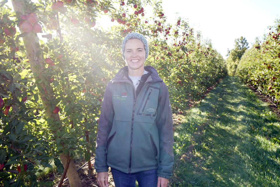 Elizabeth Pauls of Wittenbach Orchards stands among apple trees, Tuesday, Oct. 4, 2022, at the orchards in Belding, Mich. Pauls is a fifth-generation apple grower and attended Michigan State University to study agriculture. She says science-based technology for storing apples has improved markedly, even in the past few years. That means more of her family’s apples make it to consumers throughout the year. (AP Photo/Carlos Osorio)