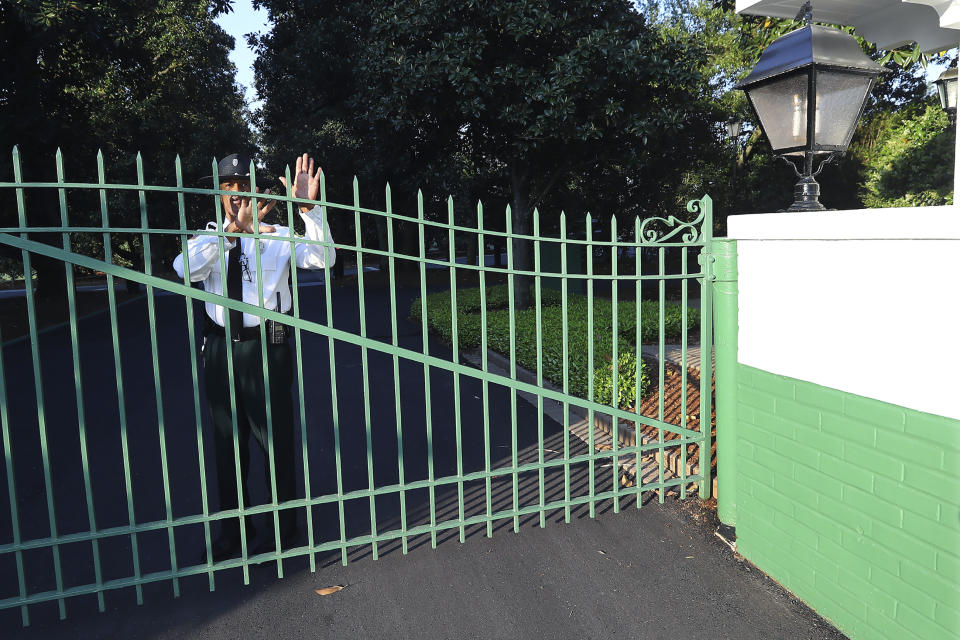 A guard at the main gate to Augusta National Golf Club warns away visitors on what would have been the first practice round for the Masters on Monday, April 6, 2020, in Augusta, Ga. Augusta National Golf Club is all locked up. Popular restaurants are shuttered, offering only curbside service if they are open at all. Washington Road, which should've been teeming with cars and commerce and humanity, is desolate instead.. (Curtis Compton/Atlanta Journal-Constitution via AP)