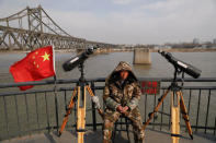 A man sits between binoculars he offers to tourists to watch the North Korean side of the Yalu River from the Broken Bridge, bombed by the U.S. forces in the Korean War and now a tourist site, in Dandong, China's Liaoning province, April 1, 2017. REUTERS/Damir Sagolj