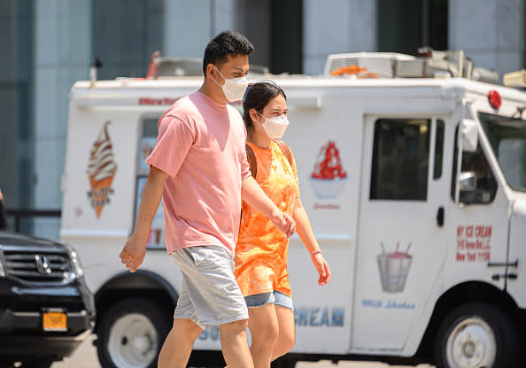 People wear protective face masks near an ice cream truck on Fifth Avenue as the city enters Phase 4 of re-opening following restrictions imposed to slow the spread of coronavirus in New York City. 