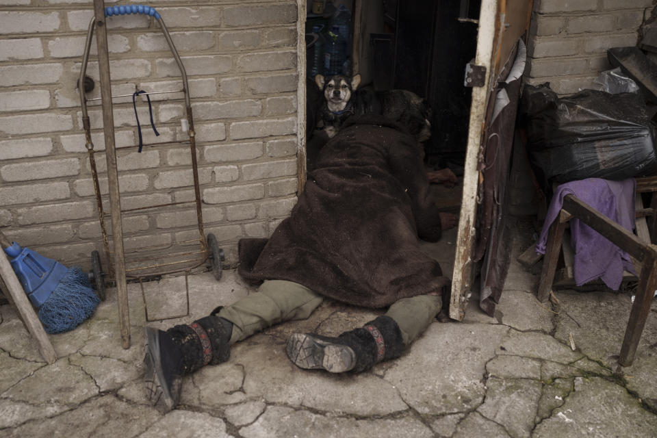 FILE - A dog stands next to the body of an elderly woman killed at the entrance of her house in Bucha, outskirts of Kyiv, Ukraine, April 5, 2022. On the northwestern fringes of the Ukrainian capital, Bucha had been occupied by Russian forces for about a month, taken as they swept toward Kyiv at the start of the invasion of Ukraine that began in late February 2022. The scenes that emerged from this town near Kyiv a year ago after it was retaken from Russian forces have indelibly linked its name to the savagery of war. (AP Photo/Felipe Dana, File)