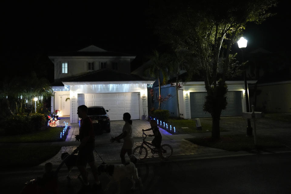 Sol, second left, a 14-year-old from Argentina, walks her dog, Cosmo, along with members of her foster family, in Homestead, Fla., Monday, Dec. 18, 2023. Sol is among tens of thousands of children who have arrived in the United States without a parent during a huge surge in immigrants that's prompting congressional debate to change asylum laws. (AP Photo/Rebecca Blackwell)