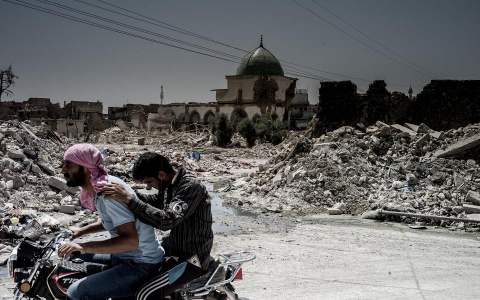 Two men pass the remnants of the Great Al Nuri mosque in the centre of the Old town of Mosul. The mosque was destroyed by IS in 2017 - Gus Palmer