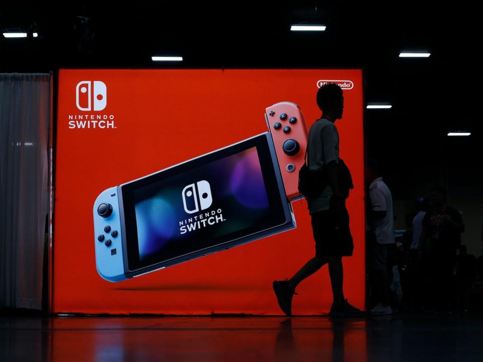 Attendees walk by an Nintendo booth showing an Nintendo Switch