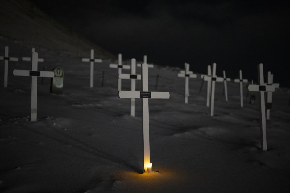 A light glows from the foot of a grave at the cemetery in Longyearbyen, Norway, Wednesday, Jan. 11, 2023. The cemetery, established in 1917 for miners -- at least 124 died on duty since then -- is now considered in the "danger zone" from increasing avalanches and landslides. A new burial ground is in the works, though the approximately 30 old graves will not be moved, the Rev. Liv Simstrand said. (AP Photo/Daniel Cole)