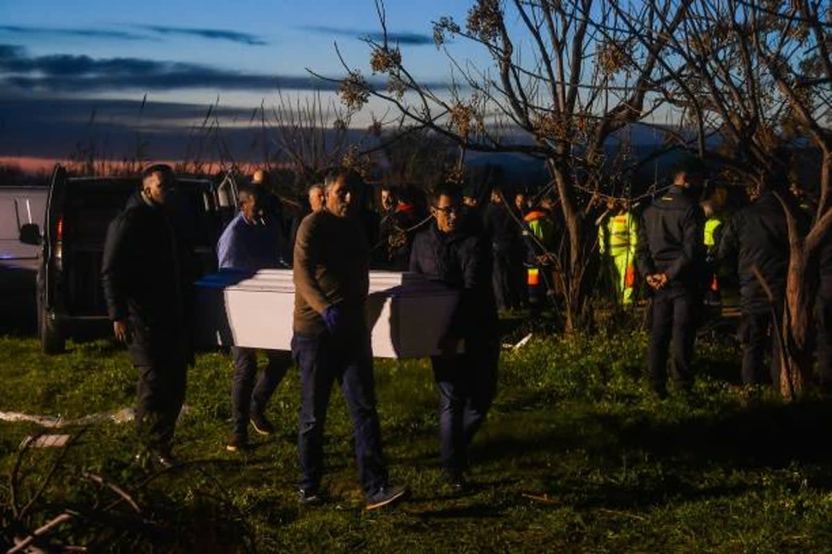 Funeral parlour employees carry away coffins containing the bodies of deceased migrants on 26 February 2023 (AFP via Getty Images)