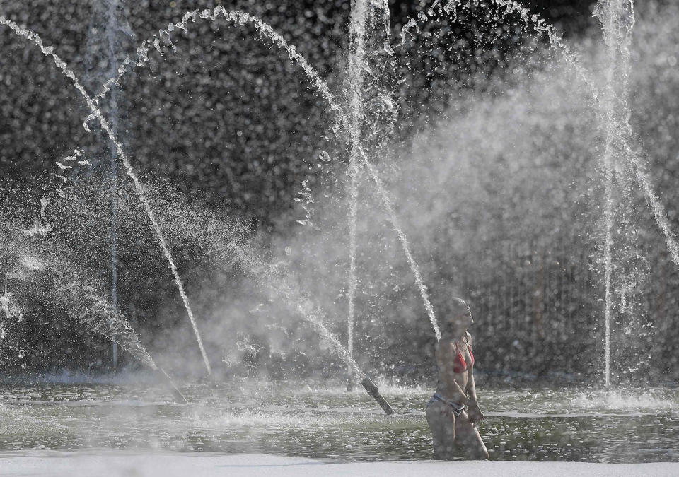 A woman cools down in fountains during unseasonably hot weather in London