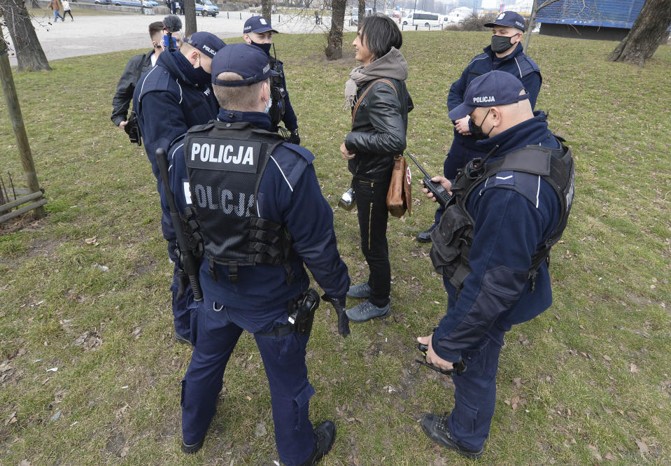 Polish police taking down the name and address of a young man to fine her for not wearing a mask in public space as Poland's authorities stepped up anti-COVID-19 measures after the nation registered three consecutive record numbers of new infections this week, in Warsaw, Poland, Friday, March 26, 2021.(AP Photo/Czarek Sokolowski)