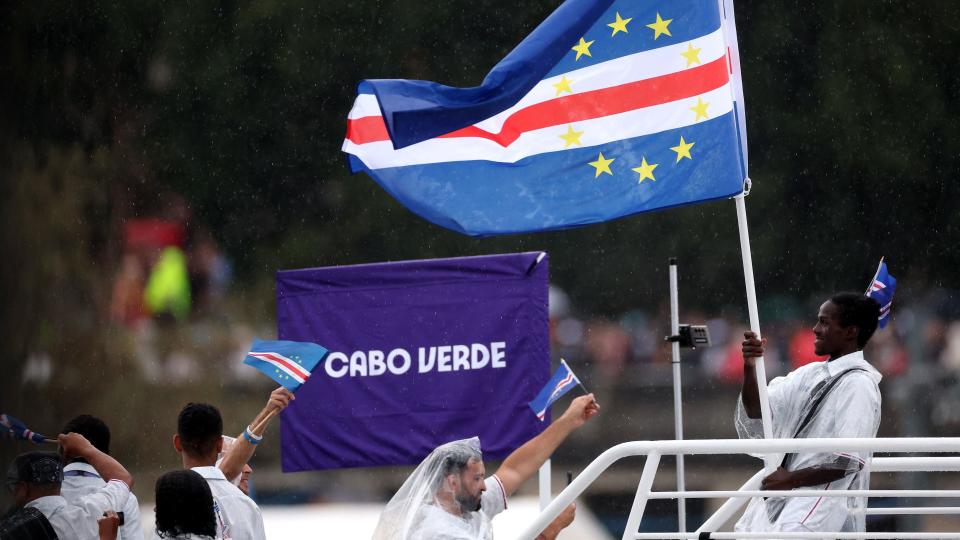 David de Pina holds the Cape Verdean flag on a boat during the opening ceremony for Paris 2024