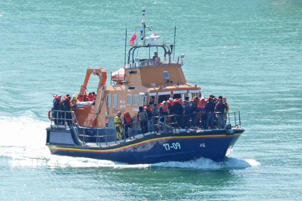 RNLI boat at sea with people thought to be migrants wearing life-jackets on board (PA Wire)