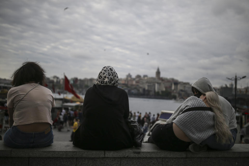 People sit in Eminonu, in Istanbul, Friday, May 28, 2021, hours before the start of a weekend curfew. (AP Photo/Emrah Gurel)