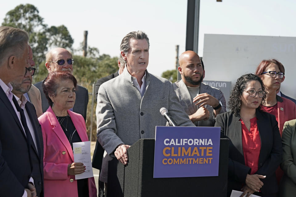 FILE - Gov. Gavin Newsom, center, is flanked by state lawmakers while discussing the package of legislation he signed that accelerates the climate goals of the nation's most populous state, at Mare Island in Vallejo, Calif., Friday, Sept. 16, 2022. Newsom opposes Proposition 30, which would raise taxes on people making more that $2 million to pay for electric vehicle infrastructure and firefight resources. (AP Photo/Rich Pedroncelli, File)