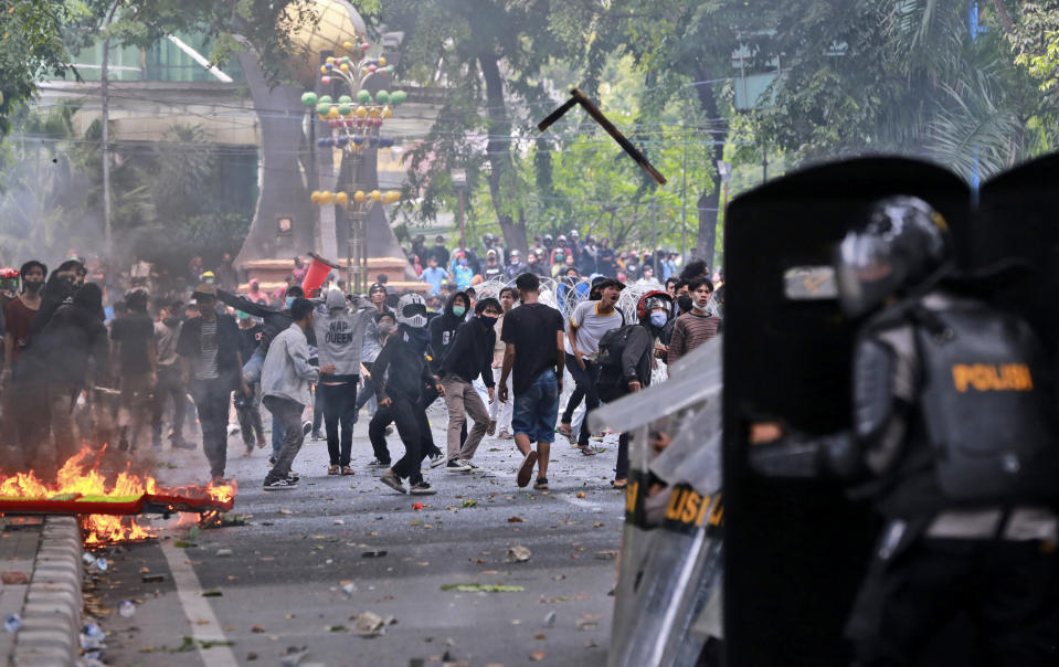 Protesters hurl debris at police during a rally against a controversial bill on job creation in Medan, North Sumatra, Indonesia, Thursday, Oct. 8, 2020. Thousands of enraged students and workers staged rallies across Indonesia on Thursday in opposition to the new law they say will cripple labor rights and harm the environment. (AP Photo/Binsar Bakkara)