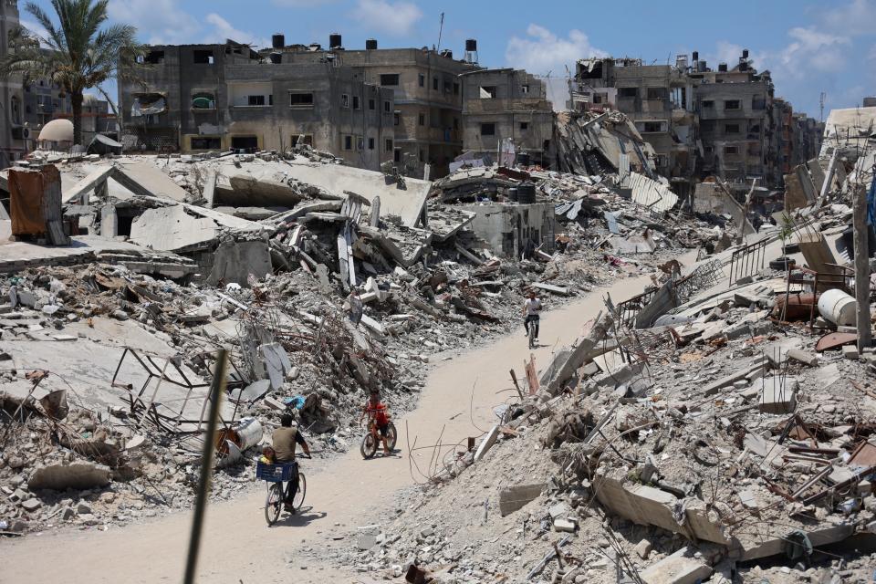 Palestinians cycle past destroyed buildings leveled as a result of Israeli bombardment in northern Gaza on July 29.