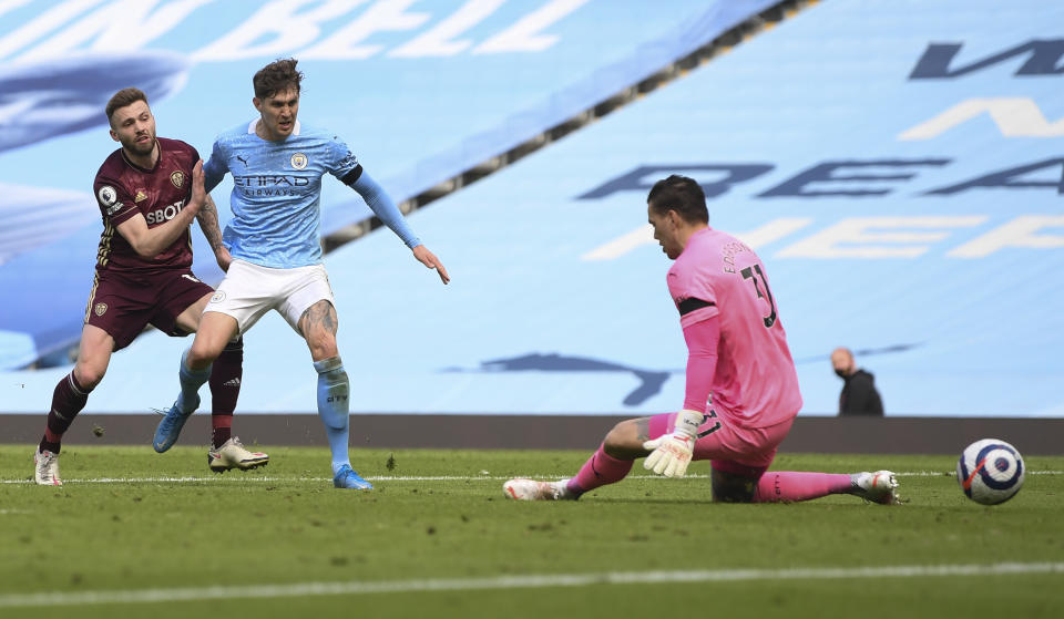 Leeds United's Stuart Dallas, left, kicks the ball past Manchester City's John Stones and goalkeeper Ederson to score his team's second goal during the English Premier League soccer match between Manchester City and Leeds United at Etihad Stadium, Manchester, England, Saturday April 10, 2021. (AP Photo/Michael Regan,Pool)