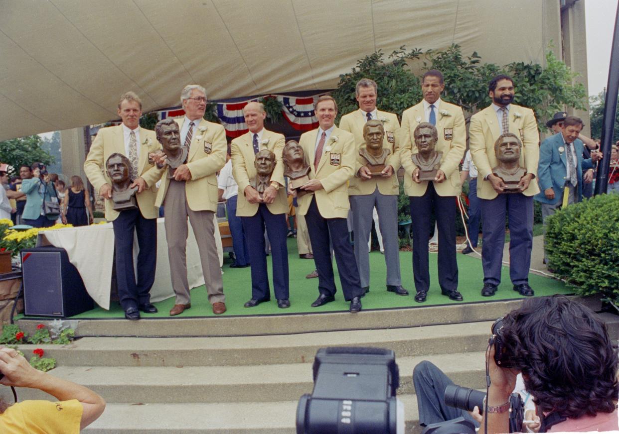 The Pro Football Hall of Fame's Class of 1990 — (from left) Jack Lambert; Bob St. Clair; Tom Landry; Bob Griese; Ted Hendricks; Buck Buchanan and Franco Harris — stand together the Enshrinement, Aug. 4, 1990, in Canton.