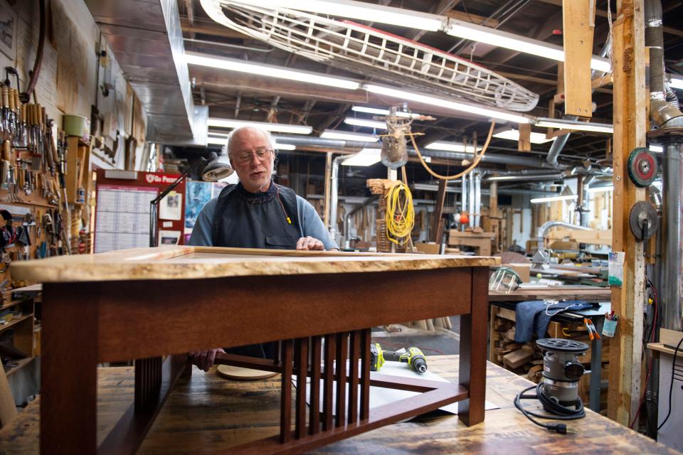 Michael McDunn, Open Studios participant, runs his fingers across the varnish of a table he built in his studio in Greenville on Wednesday, Oct. 26, 2022. 