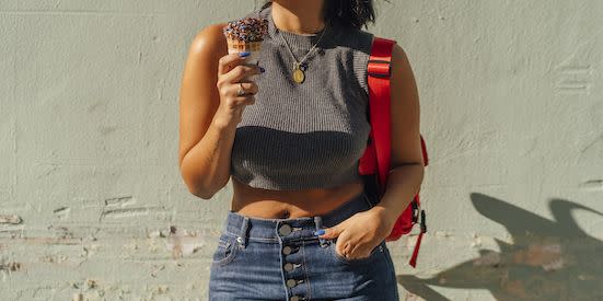 portrait of happy young woman in a crop top showing her bully button