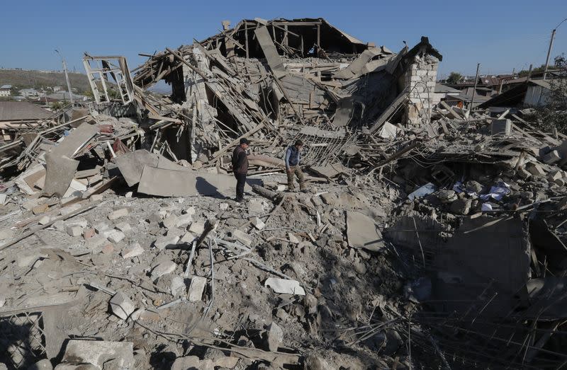 Men stand amidst the ruins of a house following recent shelling during a military conflict over the breakaway region of Nagorno-Karabakh, in Stepanakert