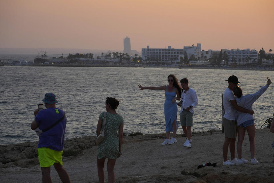 People enjoy the sea at the area of the natural 'Love' bridge, during sunset in Ayia Napa resort, in the eastern Mediterranean island of Cyprus, on Sunday, June 4, 2023. When the U.S. and U.K. in April included a handful of Cypriot nationals and Cyprus-registered companies as part of another global crackdown on 'enablers' helping Russian oligarchs skirt sanctions, the perception that the island nation somehow remains Moscow's financial lackey again loomed large. (AP Photo/Petros Karadjias)