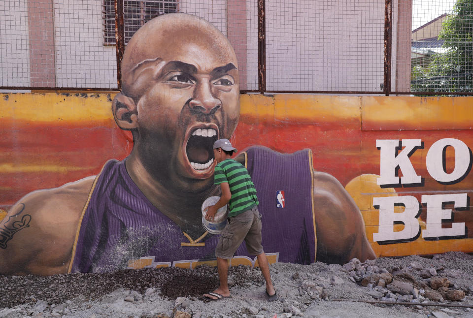 A man work beside a painting of former NBA basketball player Kobe Bryant at the "House of Kobe" basketball court in Valenzuela, north of Manila, Philippines on Monday, Jan. 27, 2020. (AP Photo/Aaron Favila)