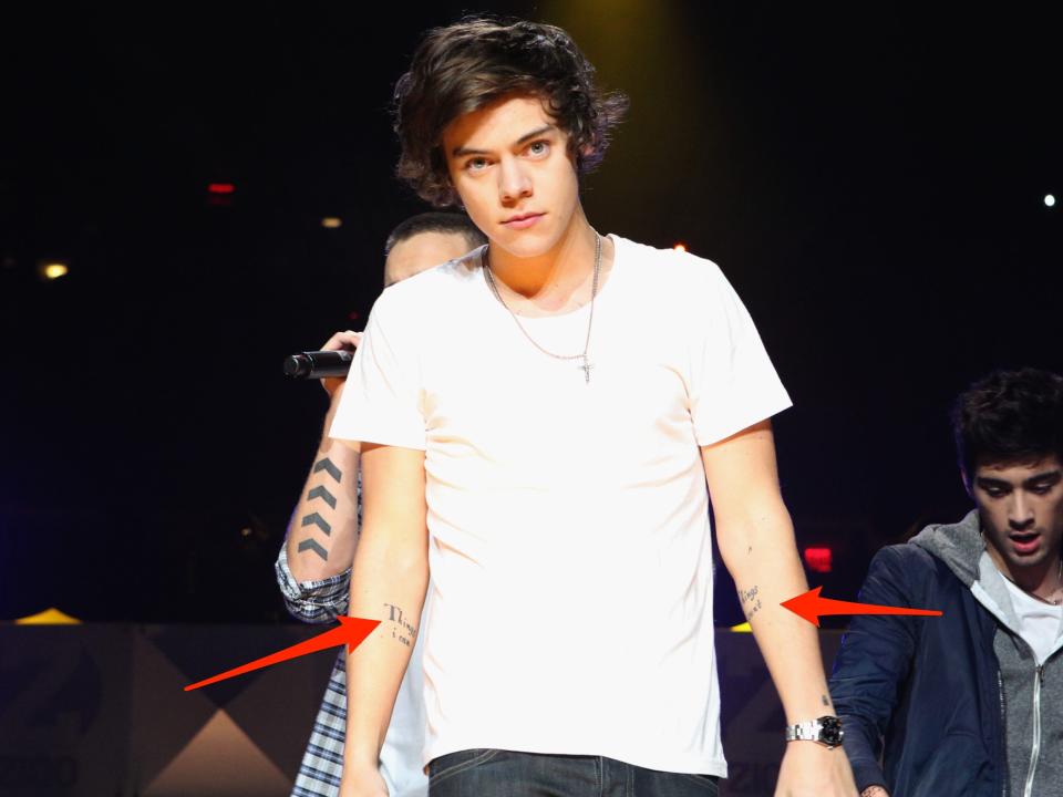 Two red arrows pointing to tattoos on Harry Styles' arms.