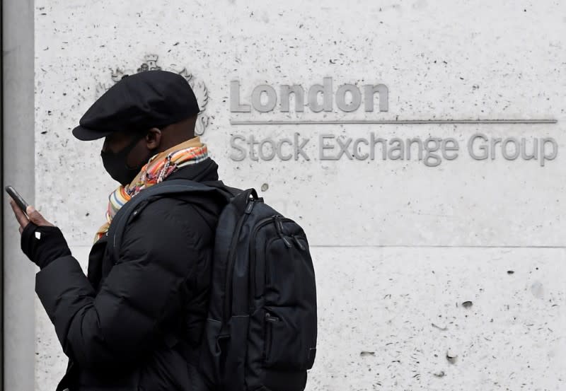 FILE PHOTO: A man wearing a protective face mask walks past the London Stock Exchange Group building in the City of London financial district.