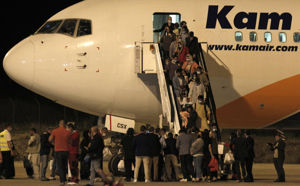 Afghan evacuees disembark a plane after landing at Skopje International Airport, North Macedonia, late Monday, Aug. 30, 2021. A first group of 149 Afghan evacuees landed late Monday in North Macedonia, where they will stay for a few months pending resettlement elsewhere. (AP Photo/Boris Grdanoski)