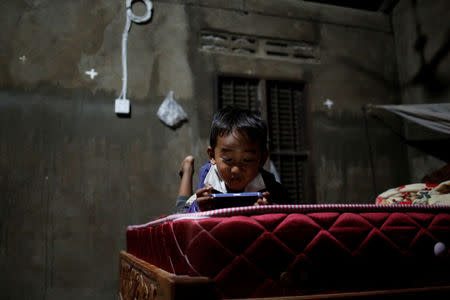 Seng Tharith, 4, the son of Khen Srey Touch, plays with a cellphone in his house in Kampong Speu, Cambodia, July 5, 2018. Khen Srey Touch is nine months pregnant and works at Complete Honour Footwear Industrial, a footwear factory owned by a Taiwan company. She works 10 hours a day, six days a week and earns $240 a month. "I am the main breadwinner of the house," she said. REUTERS/Ann Wang