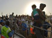 A Djibouti security official carries a young girl down a gangway as people fleeing Yemen arrive aboard a dhow on April 14, 2015 at a the port of Djibouti after crossing the Gulf of Aden