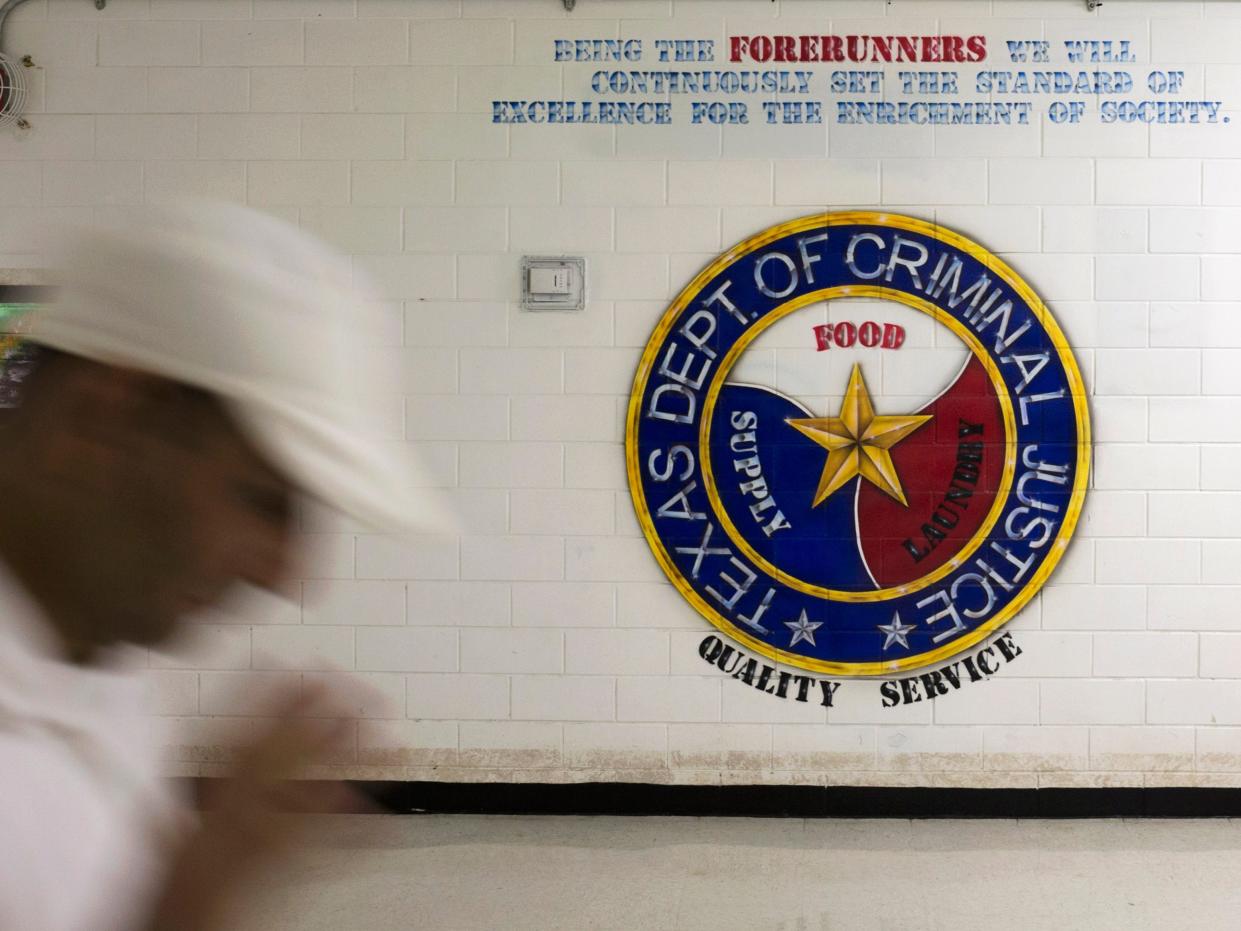 A person walks past the logo of the Texas Department of Criminal Justice on a wall.