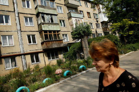 A woman walks past a damaged building in the Oktyabrsky district of Donetsk, Ukraine, September 8, 2017. REUTERS/Alexander Ermochenko