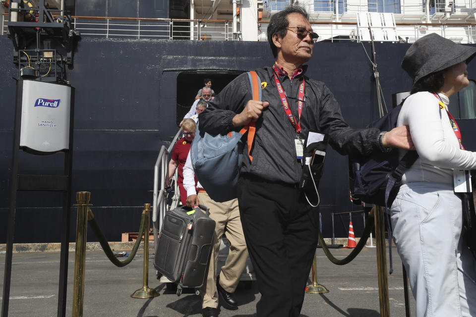 Passengers of the MS Westerdam disembark at the port of Sihanoukville, Cambodia, Saturday, Feb. 15, 2020. After being stranded at sea for two weeks because five ports refused to allow their cruise ship to dock, the passengers of the cruise ship were anything but sure their ordeal was finally over. (AP Photo/Heng Sinith)