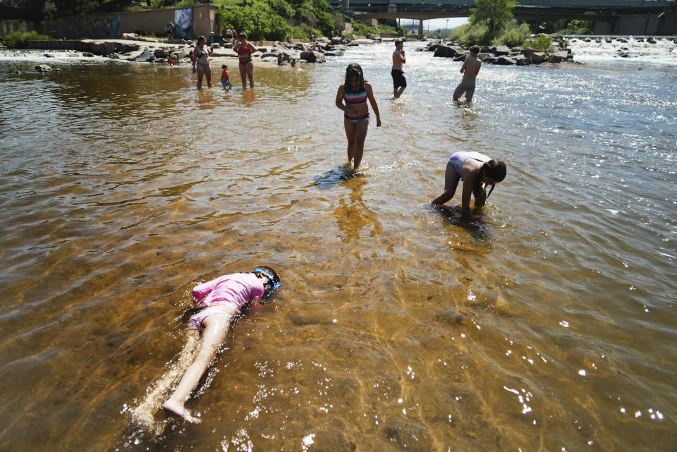 Children play in the water at the confluence of the South Platte River and Cherry Creek in Denver, Monday, June 14, 2021. By mid-afternoon, the temperature hit 96 degrees Fahrenheit as part of the heat wave sweeping across the Western United States.(AP Photo/Brittany Peterson)