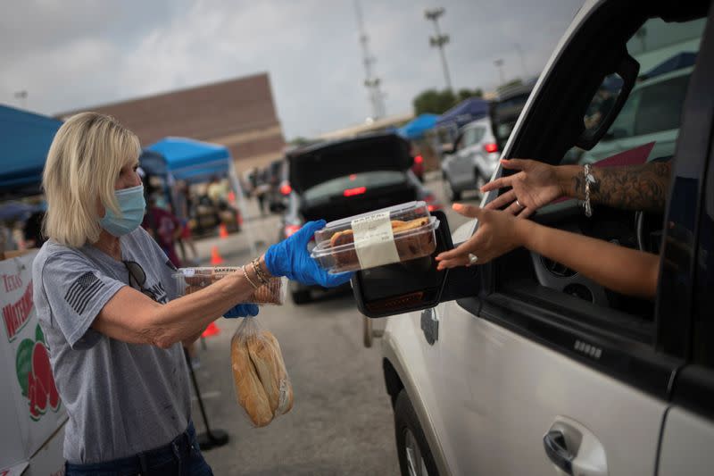 Volunteer give food to residents economically affected by COVID 19 pandemic during San Antonio Food Bank distribution in Texas